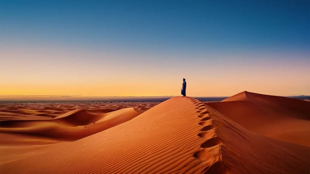 A lone figure standing on Sahara dunes at sunset in Morocco — autumn is the best time to visit Morocco for desert treks with warm days and cool nights