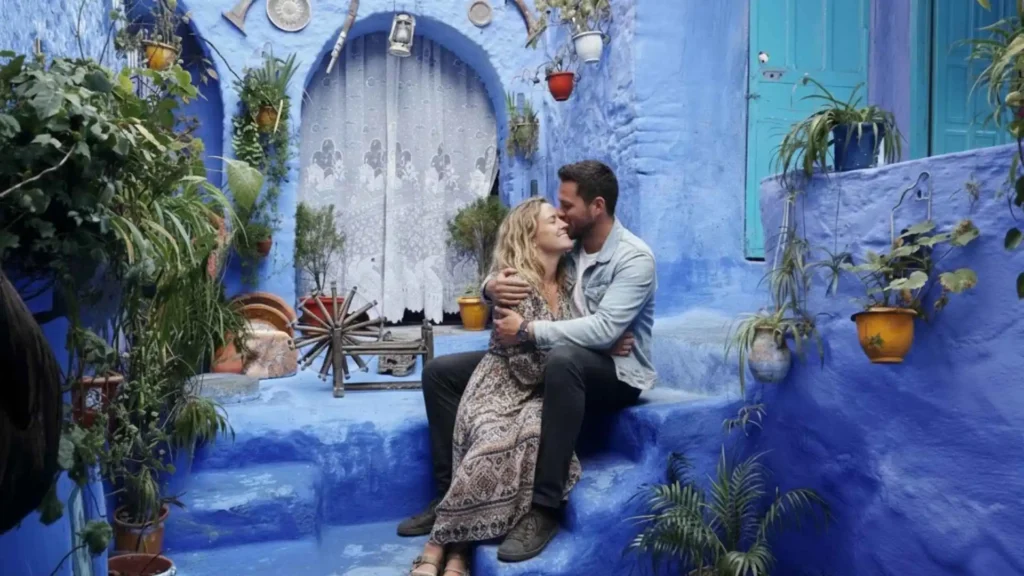 Couple sitting in a blue alley in Chefchaouen Morocco surrounded by green plants — a perfect peaceful honeymoon in Morocco destination