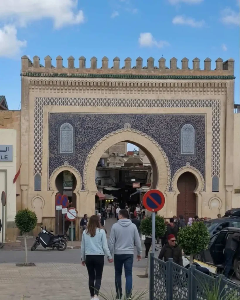 Couple walking hand in hand toward Bab Boujloud in Fes — one of the best honeymoon in Morocco destinations for couples seeking history and authenticity