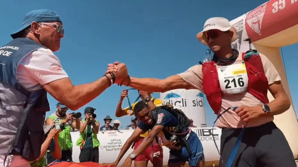 Competitor at the Marathon des Sables finish line in the Moroccan Sahara shaking hands with a race official