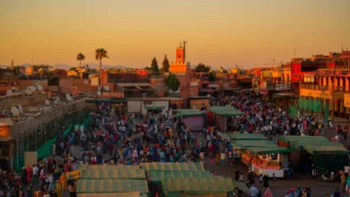 Aerial evening view of Jemaa el-Fna square in Marrakech packed with crowds and food stalls at sunset with the Atlas Mountains on the horizon — the ultimate guide to the best time to visit Morocco in 2026