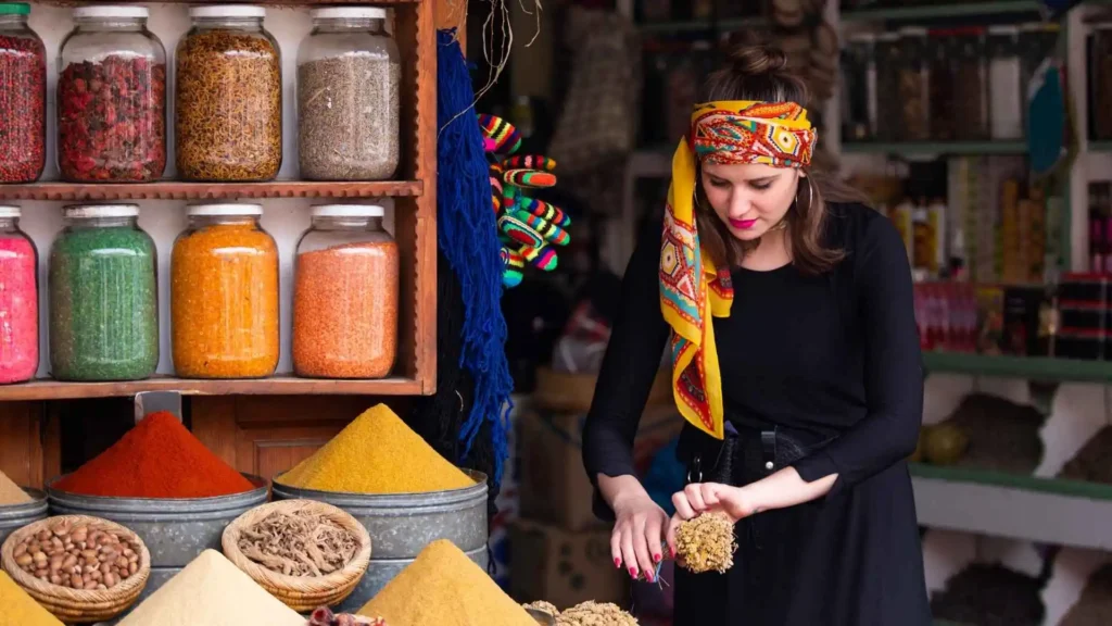 A traveler browsing spices and herbs at a Moroccan market stall — knowing how to bargain is essential for what to buy in Morocco