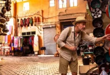 What to buy in Morocco — a traveler browsing handcrafted ceramics and lanterns in a Moroccan souk