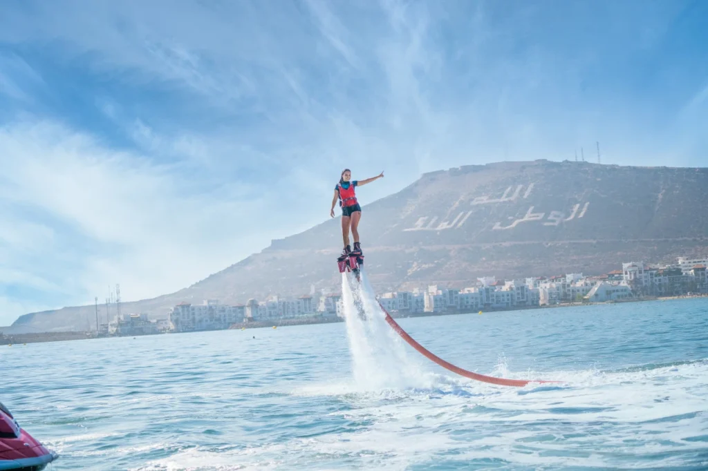 Flyboarding above the water in Agadir Morocco with the iconic Agadir Oufella hill and the city's coastline in the background