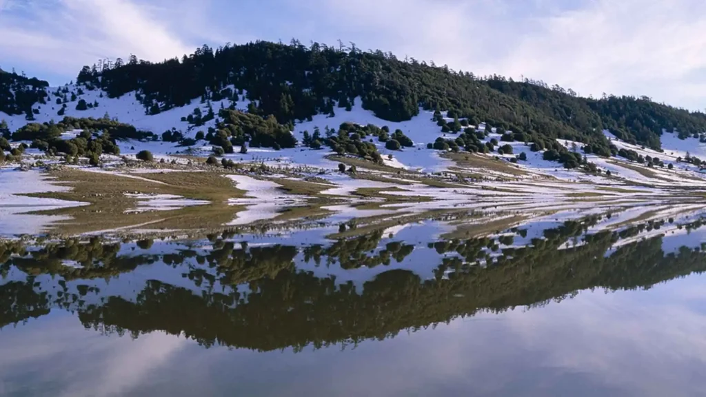 Snow-covered mountains reflected in a lake near Ifrane, Morocco — winter is the best time to visit Morocco for low crowds and Atlas Mountain scenery