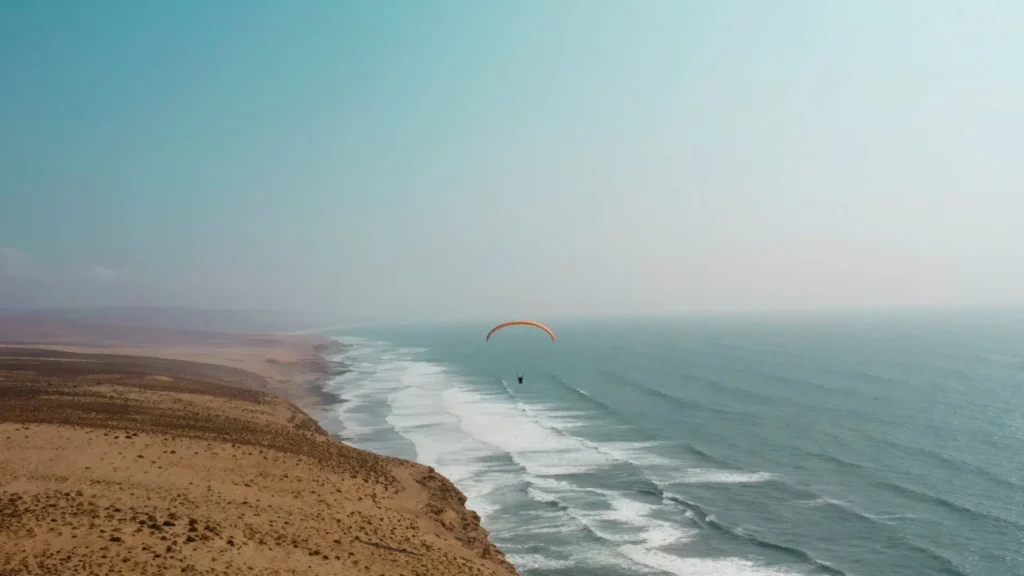 Paragliding over Aglou beach on Morocco's Atlantic coast where barren cliffs meet ocean waves in the Souss-Massa region