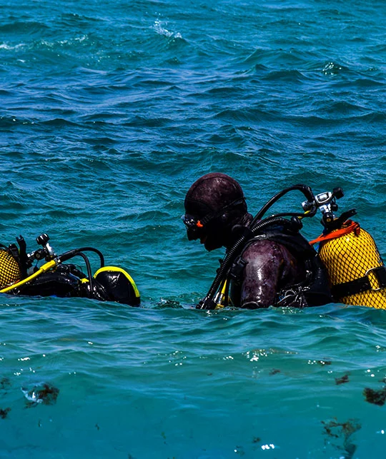 Two scuba divers preparing to descend into the clear waters off Morocco's coast for an underwater exploration dive